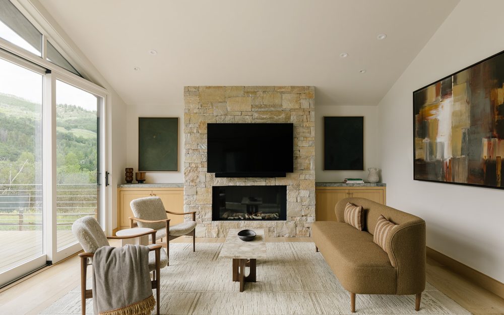 West Aspen Retreat living room with a stone fireplace and contemporary furnishings.