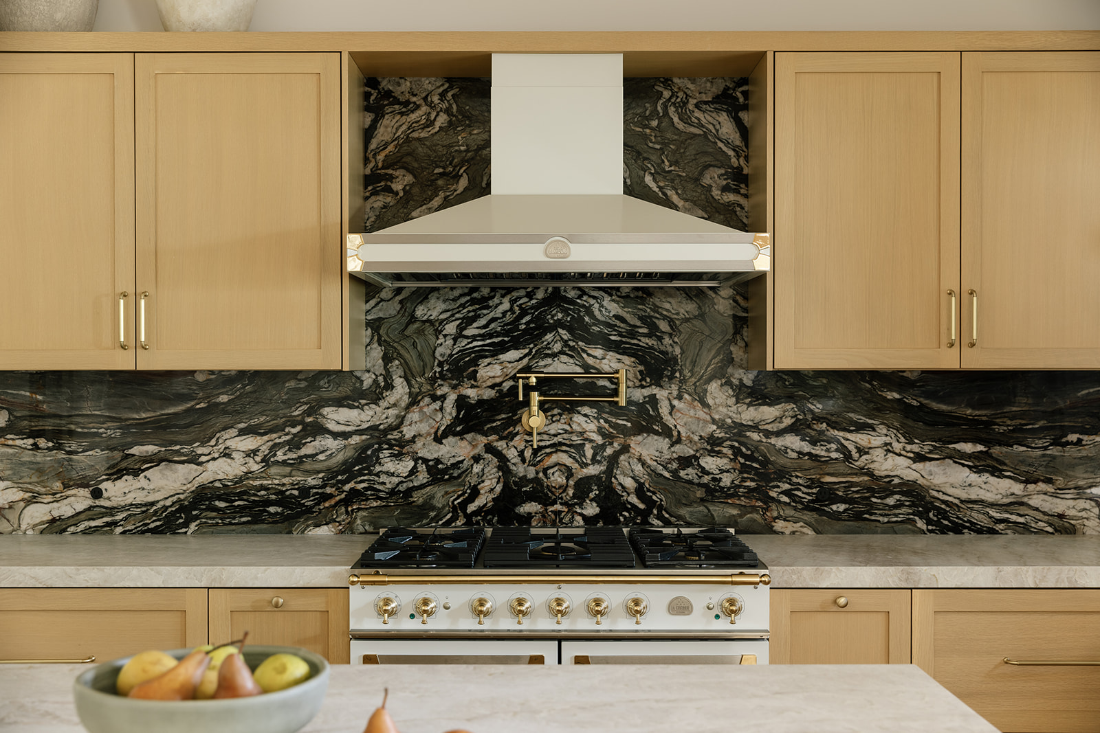 white Kitchen hood, oak shaker cabinets and quartz stone backsplash