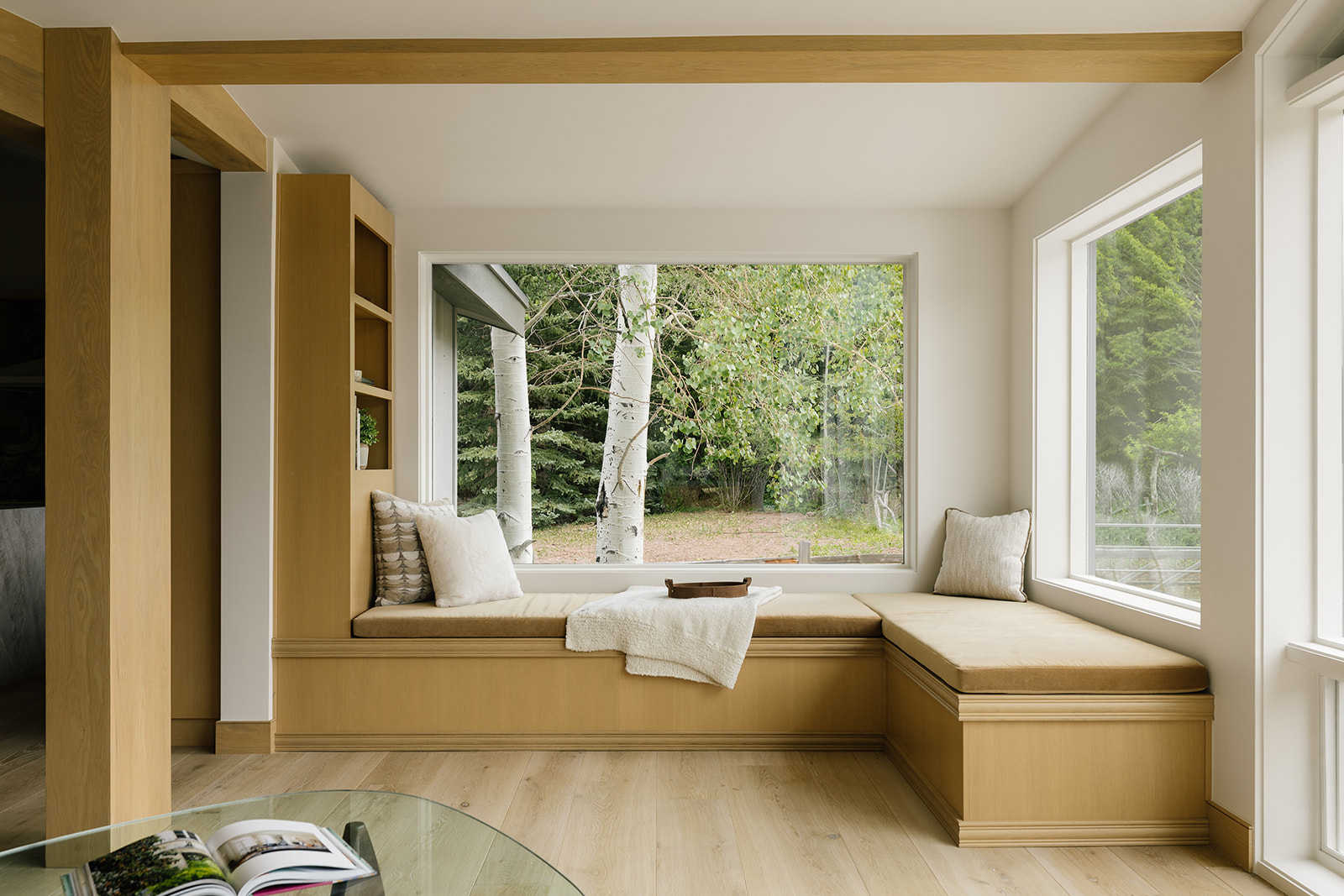 Built-in oak reading nook with upholstered seating, bookshelves and a window bringing in natural light.