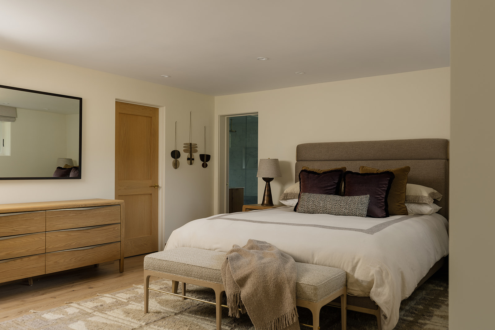 Primary bedroom with upholstered bed, neutral rug and oak dresser